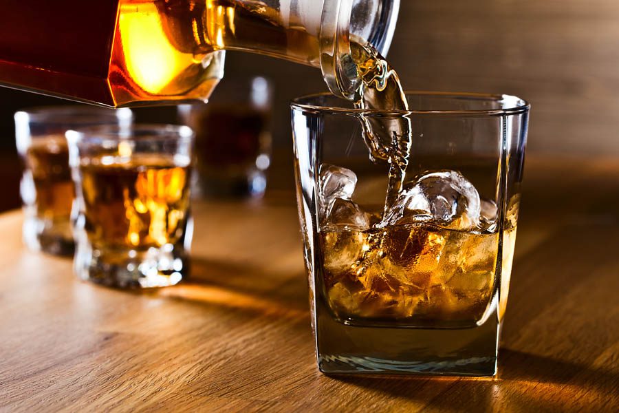 Distillery Insurance - Pouring Whiskey Into a Bar Glass with Fancy Ice Cubes