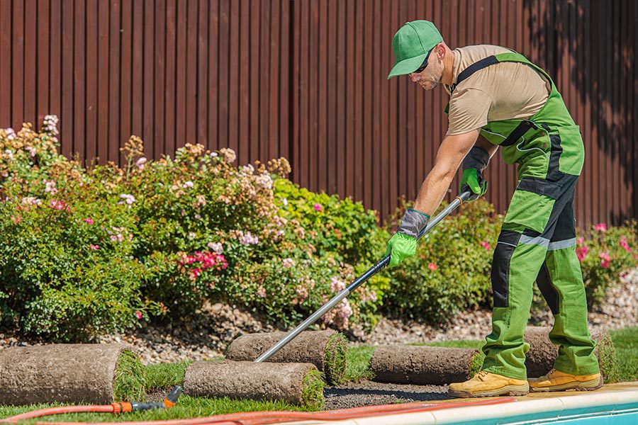Specialized Business Insurance - a Landscaper in Cap and Overalls Lays Out Sod Along the Edge of a Swimming Pool