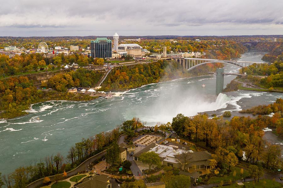 Tonawanda, NY Insurance - Niagra River and Surrounding Towns on a Fall Day, Waterfall Feeding Into the River, Trees Turning Red and Orange